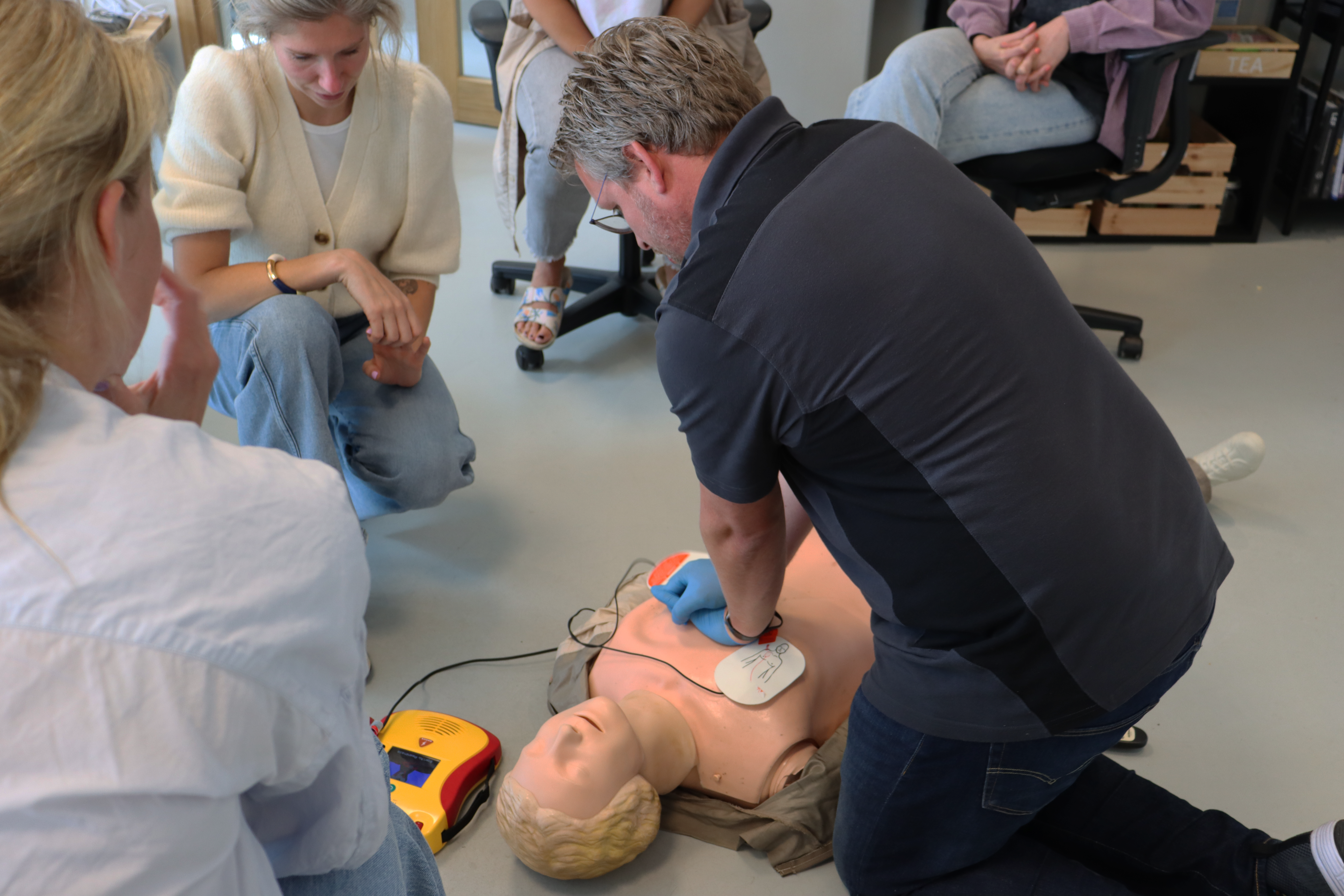Groep mensen oefenen een noodsituatie met een brandblusser tijdens een BHV-training.